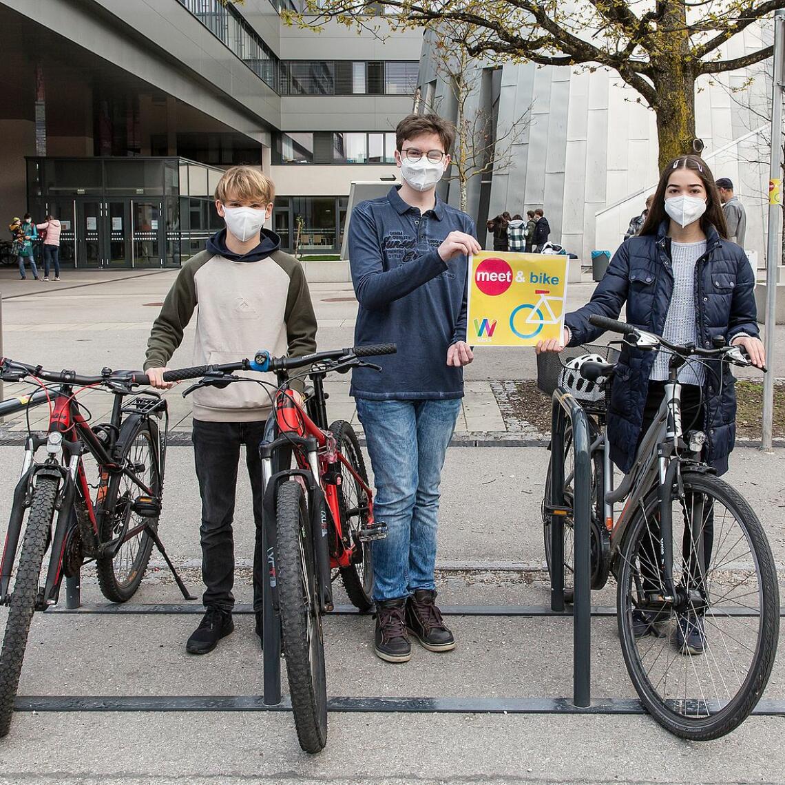 3 Schüler:innen präsentieren Fahrräder und Tafel meet&bike