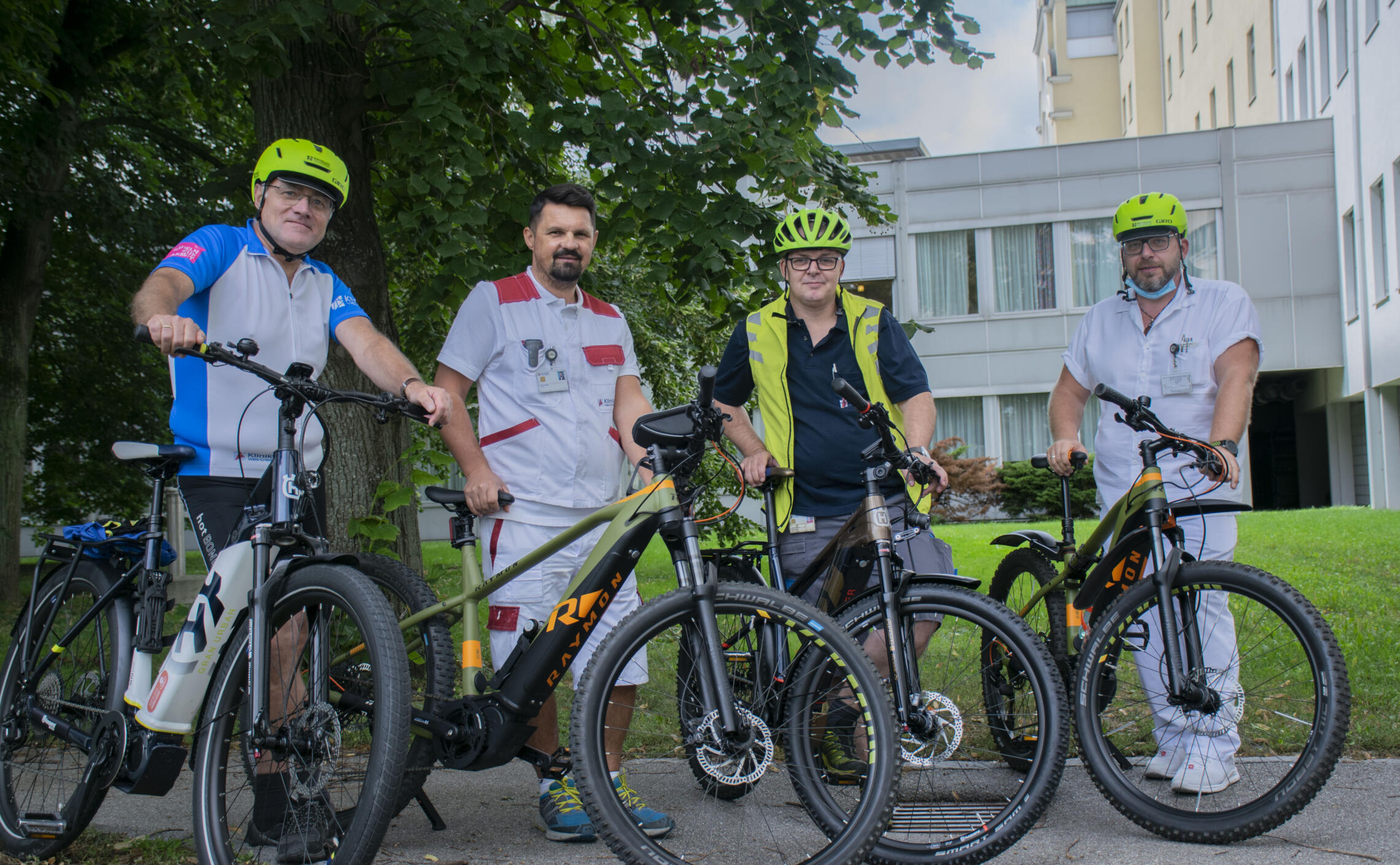 Vier Mitarbeiter des Klinikums Wels-Grieskirchen stehen mit ihren neuen Jobrädern vor dem Krankenhausgebäude.