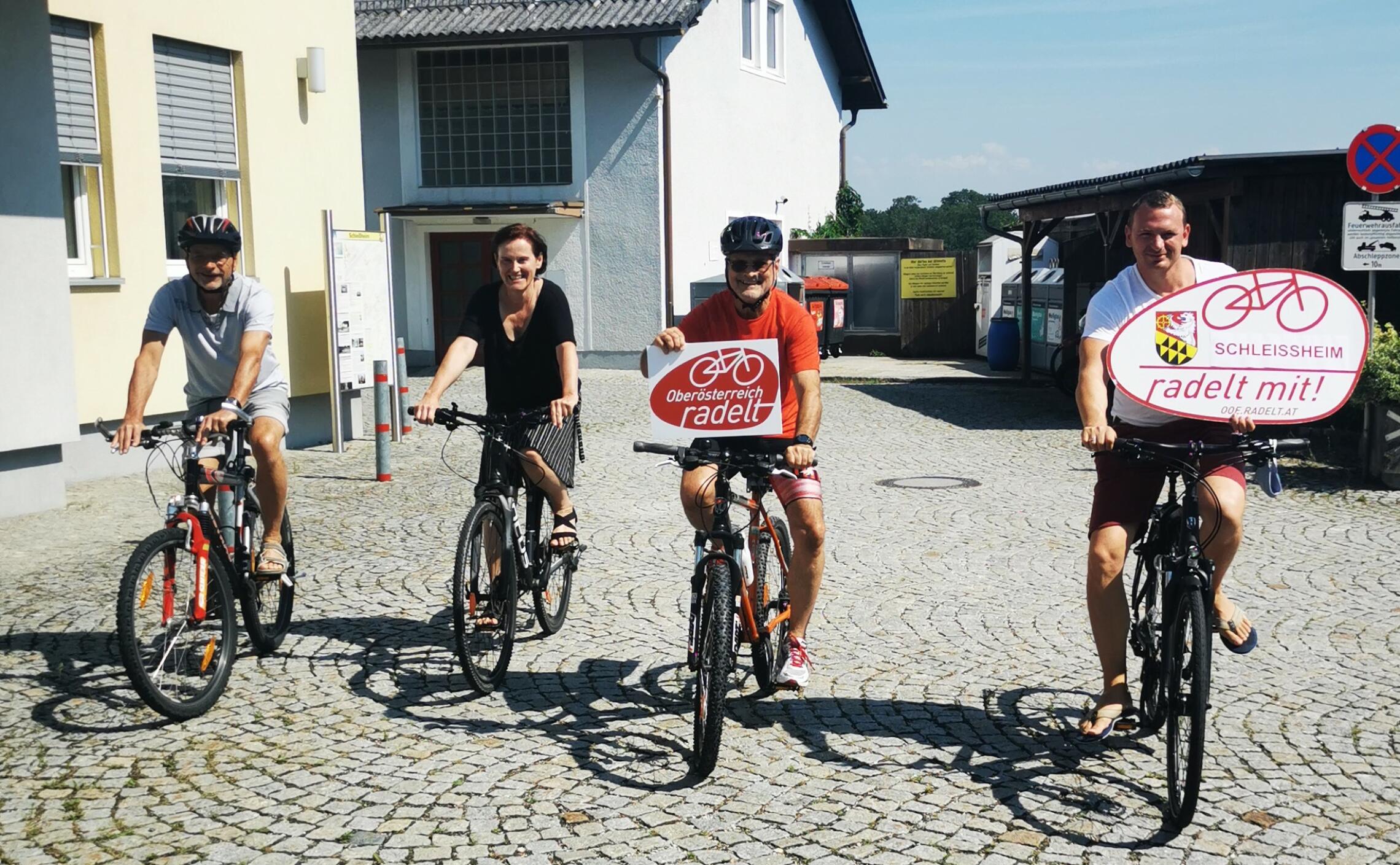 4 Erwachsene fahren mit dem Fahrrad und präsentieren Tafeln 