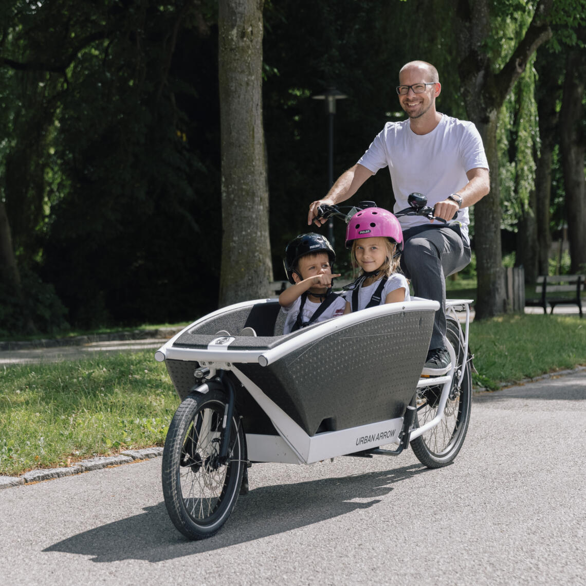 Junger Mann testet Urban Arrow Transportrad mit 2 Kindern in der Transportkiste
