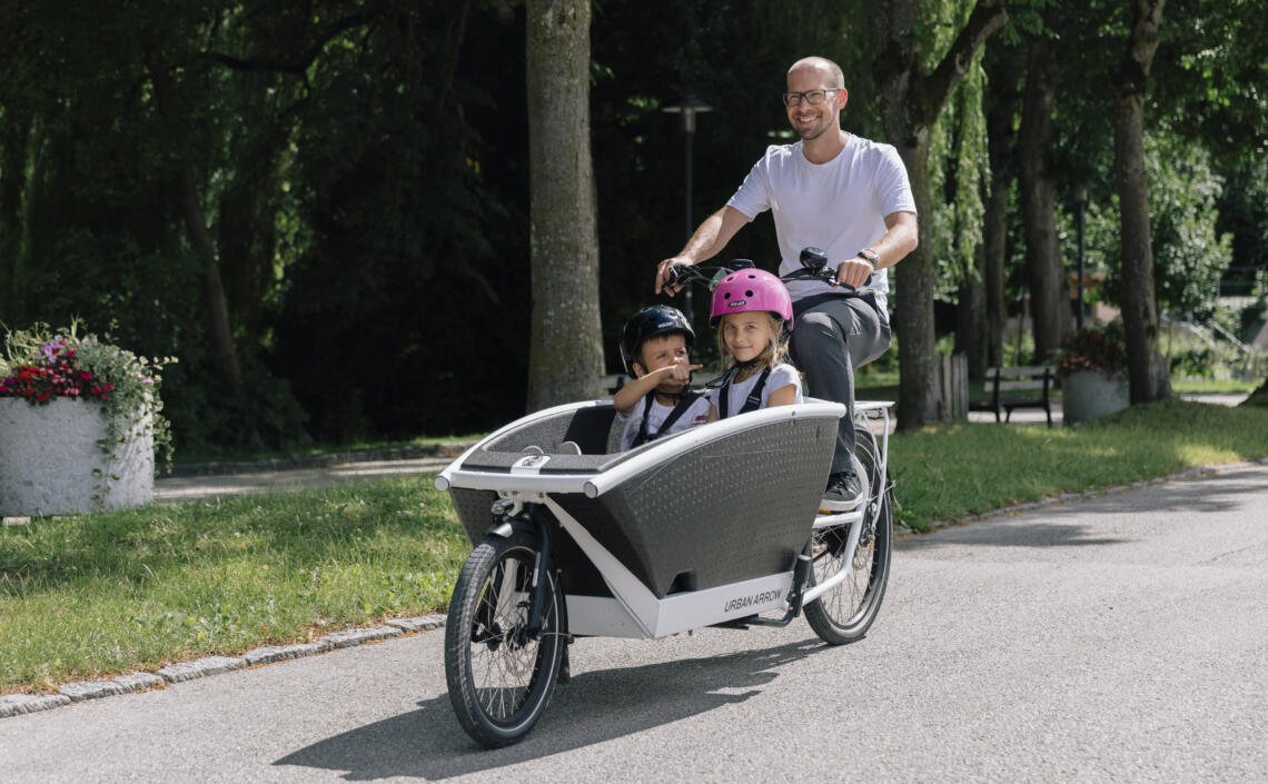 Junger Mann testet Urban Arrow Transportrad mit 2 Kindern in der Transportkiste