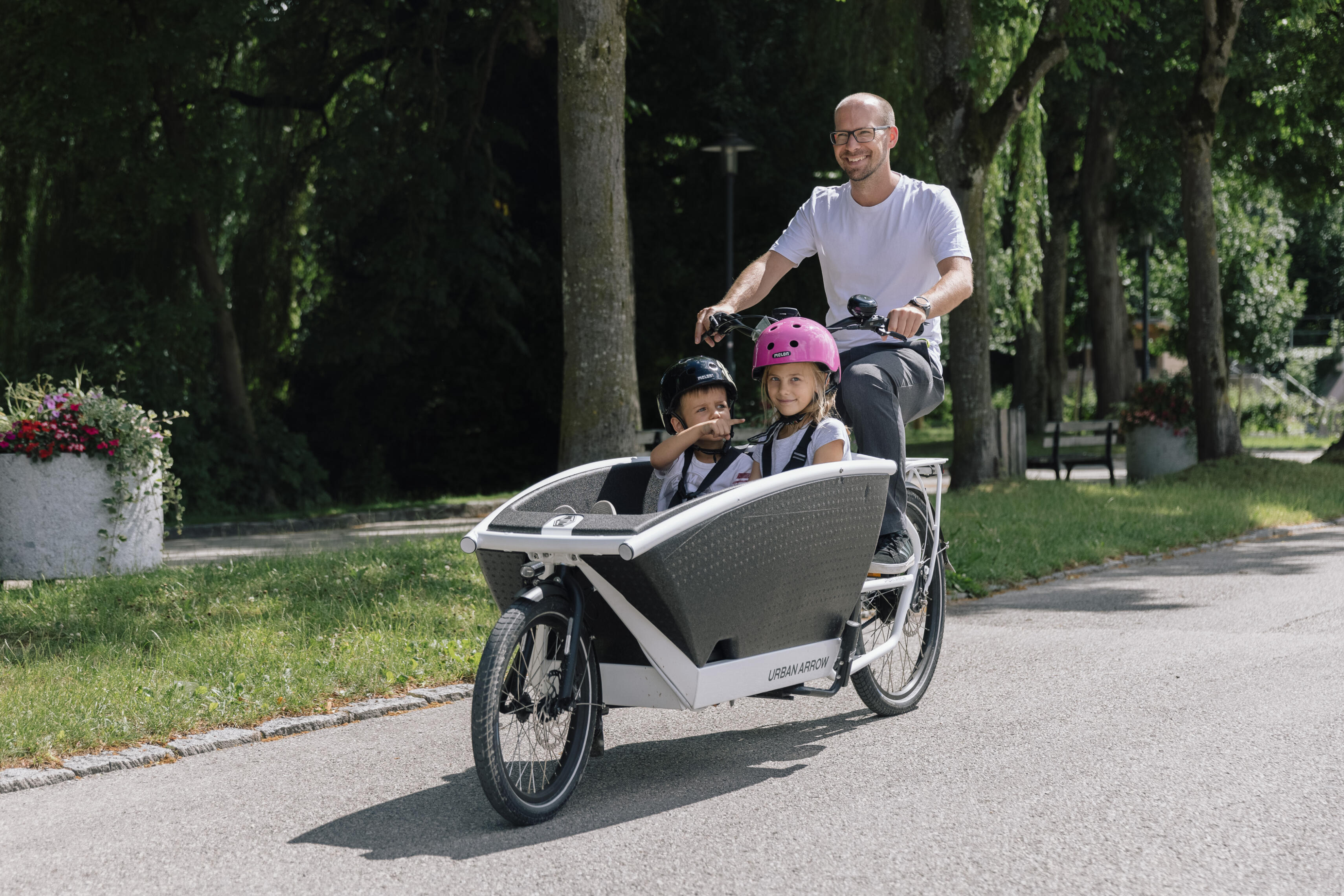 Junger Mann testet Urban Arrow Transportrad mit 2 Kindern in der Transportkiste