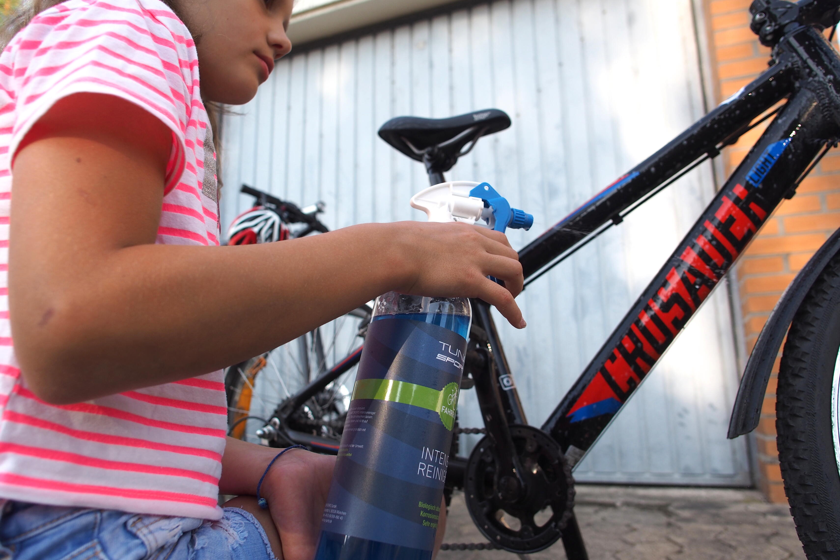Mädchen besprüht Fahrrad mit Fahrrad - Intensiv-Reiniger