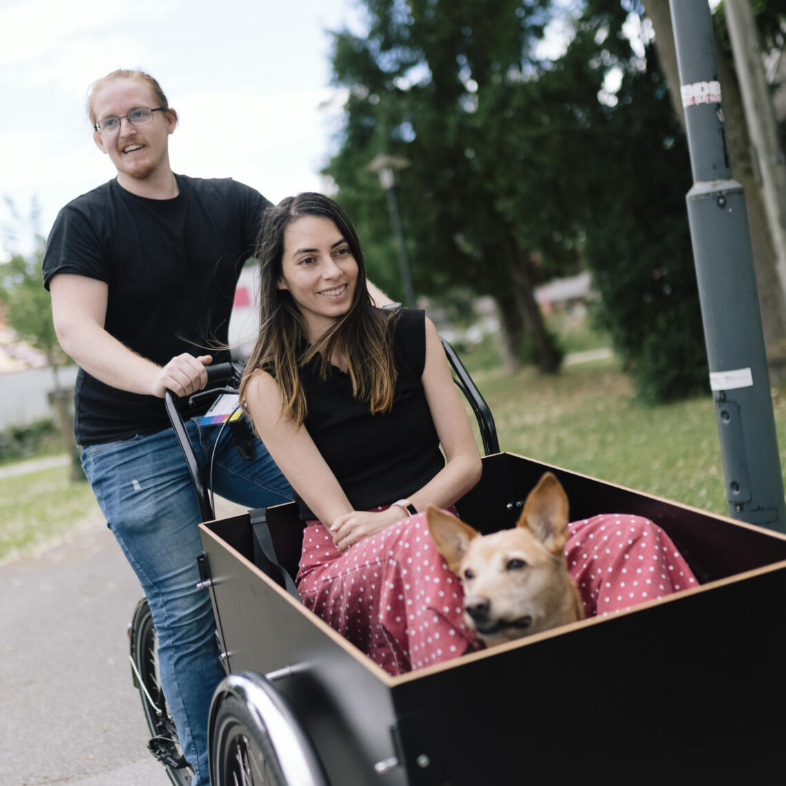 Frau sitzt gemeinsam mit ihrem Hund in der Kiste eines Transportrads