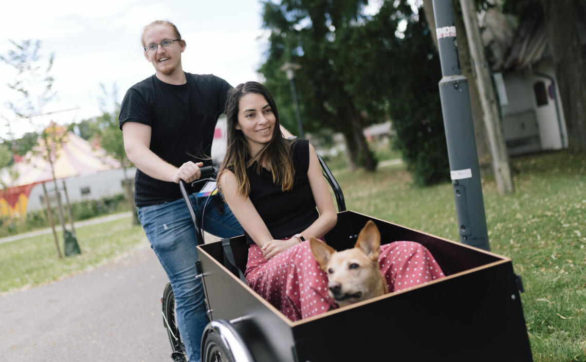 Frau sitzt gemeinsam mit ihrem Hund in der Kiste eines Transportrads