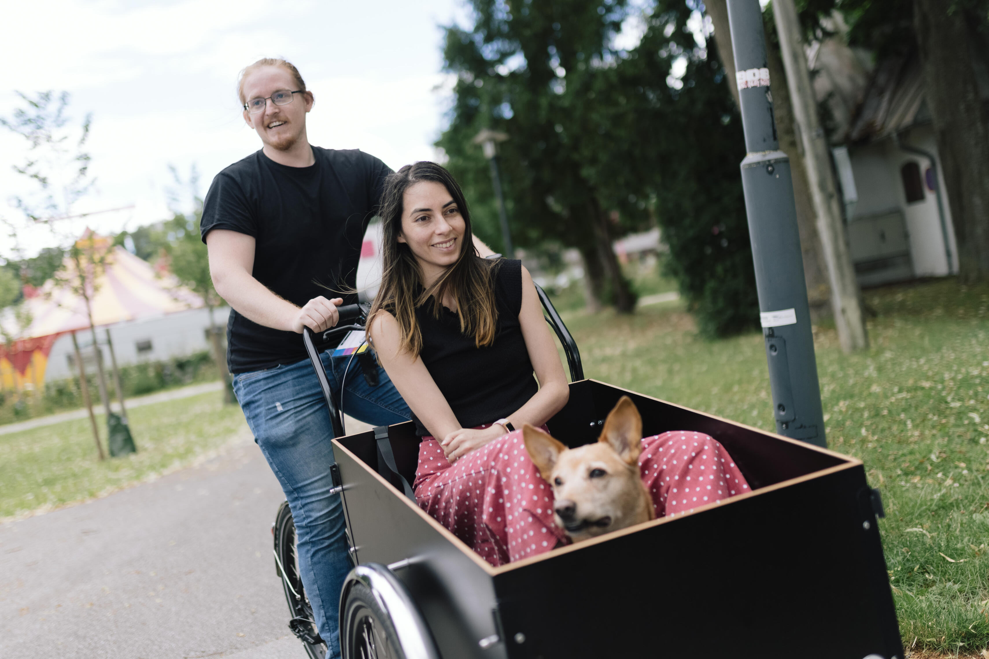 Frau sitzt gemeinsam mit ihrem Hund in der Kiste eines Transportrads
