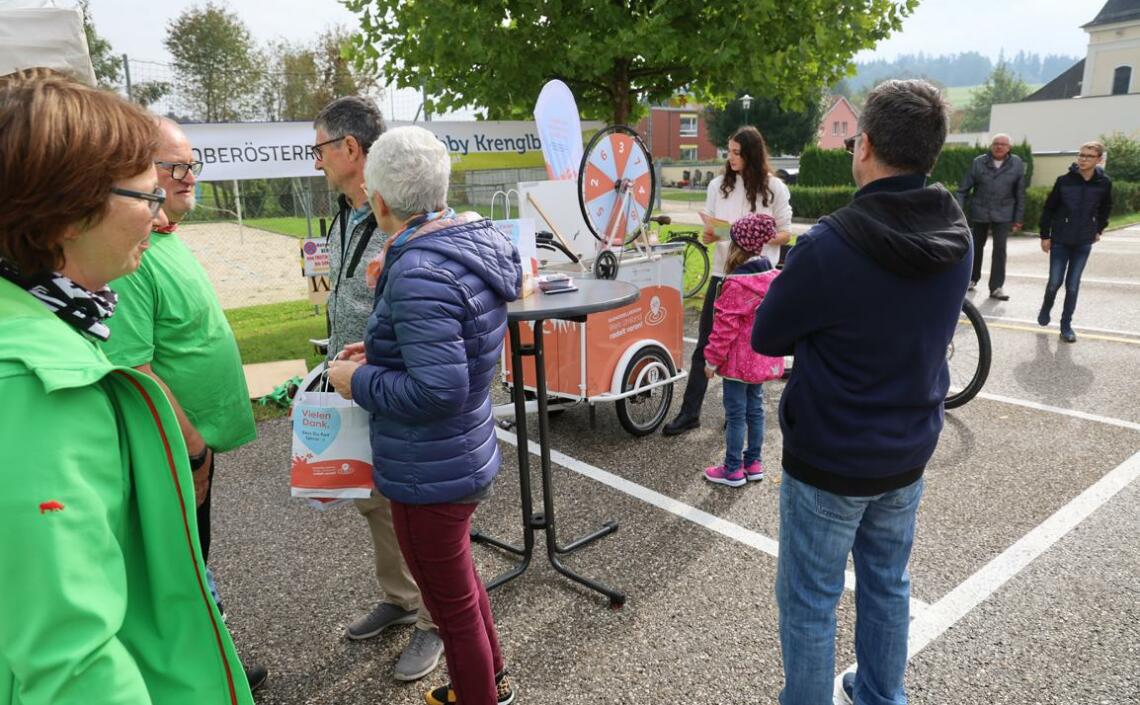 Personen stehen bei Parkplätze. Es gibt ein Lastenrad mit Glücksrad