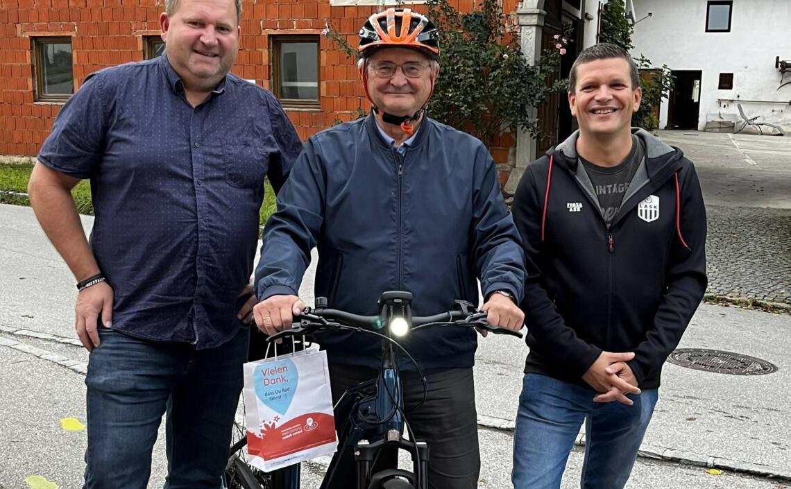 3 Herren präsentieren Fahrrad und Danke-Sackerl 
