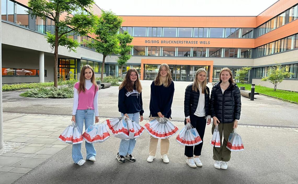 5 Schülerinnen präsentieren Danke-Sackerl vor der Schule BG/BRG Brucknerstrasse Wels