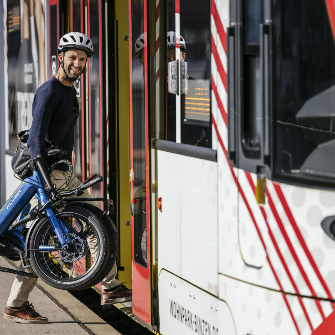 Herr trägt zusammengeklapptes Klapp-Rad in Straßenbahn-