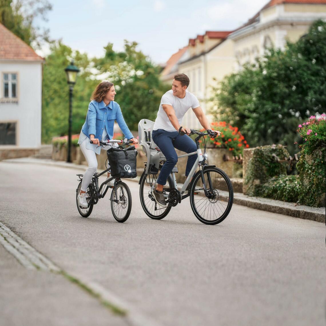 Dame und Herr fahren gemeinsam Fahrrad und lächeln sich an.