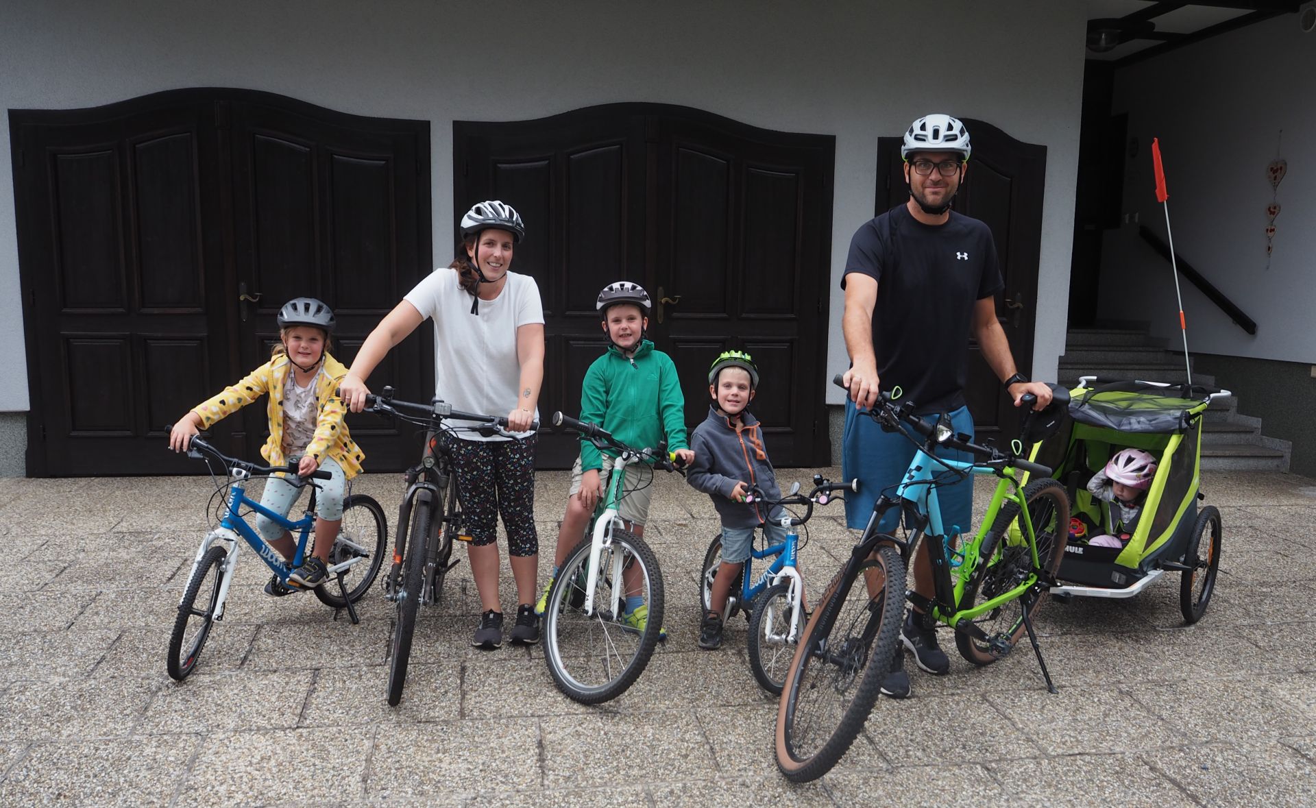6 köpfige Familie im Portrait mit Fahrrädern und Radanhänger