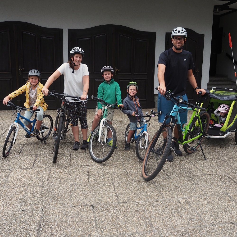Familie mit vier Kindern auf Fahrrädern und Radanhänger