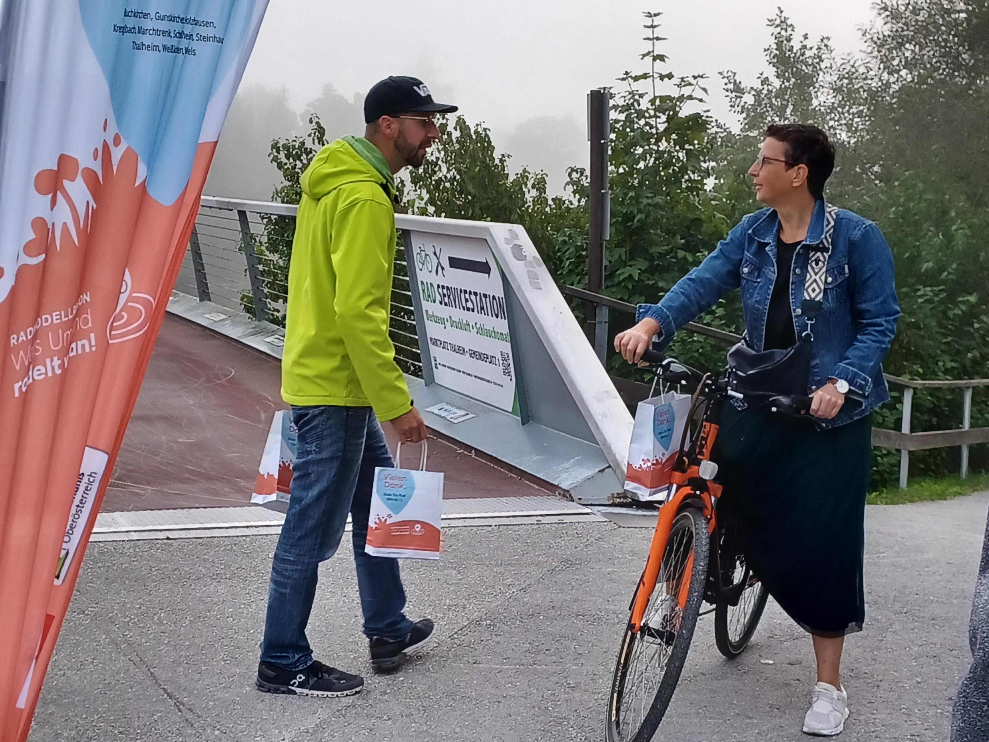 Herr gibt Danke-Sackerl einer Dame auf dem Fahrrad