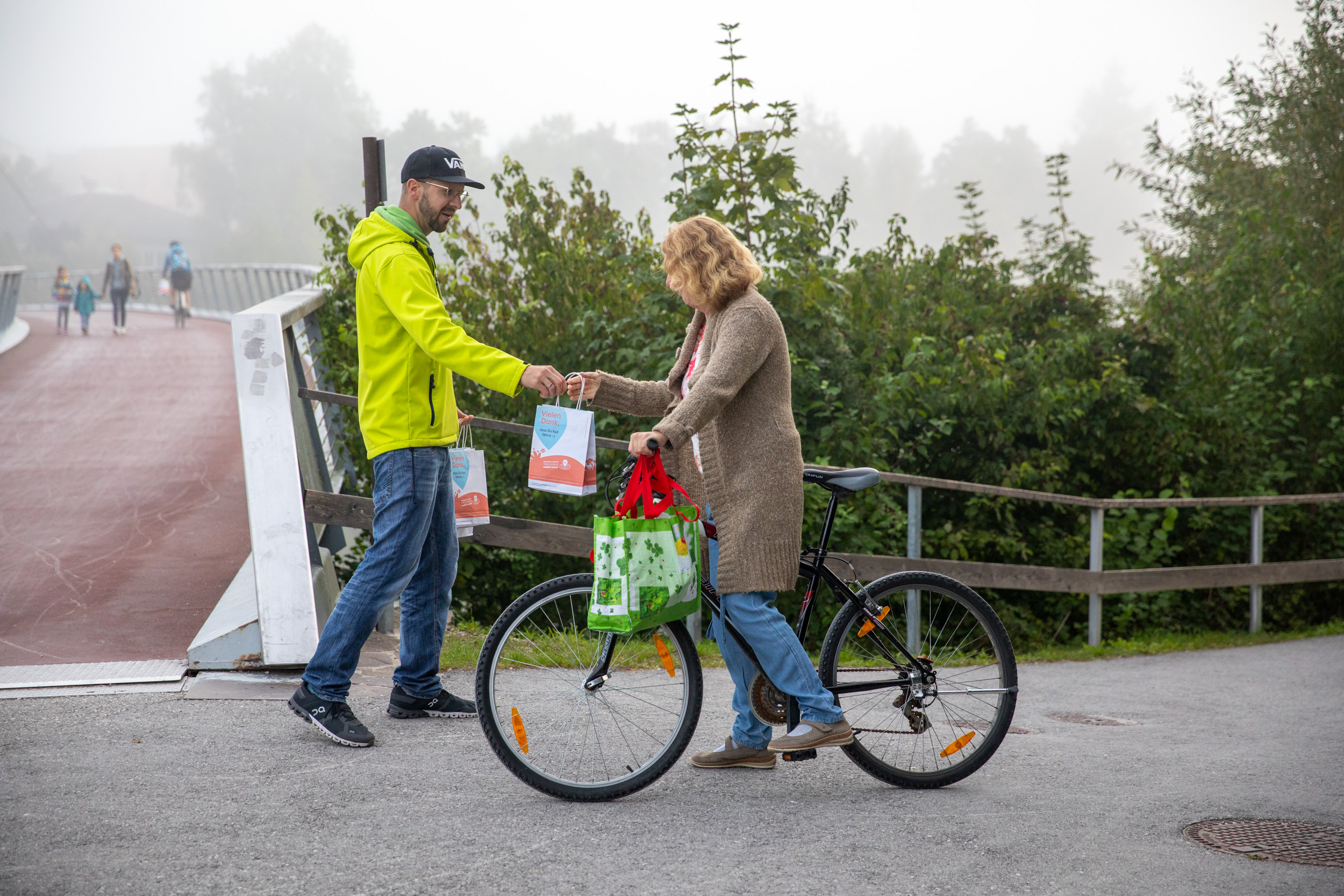 Herr gibt Danke-Sackerl einer Dame auf dem Fahrrad