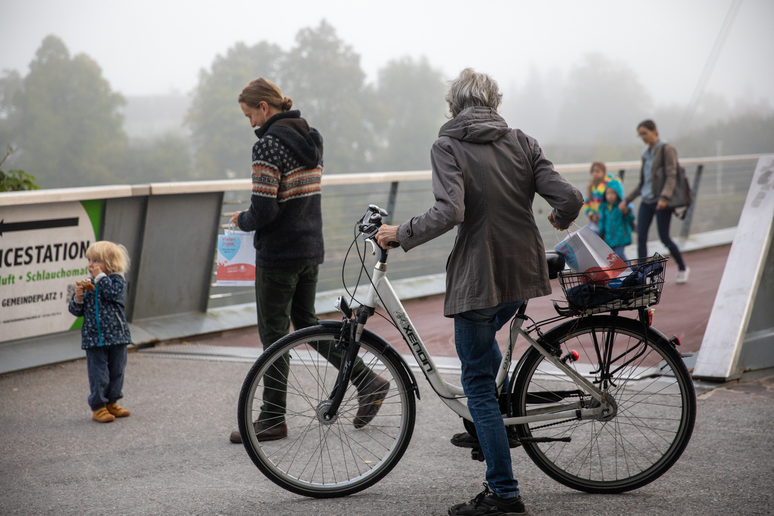 Dame mit Fahrrad auf einer Brücke