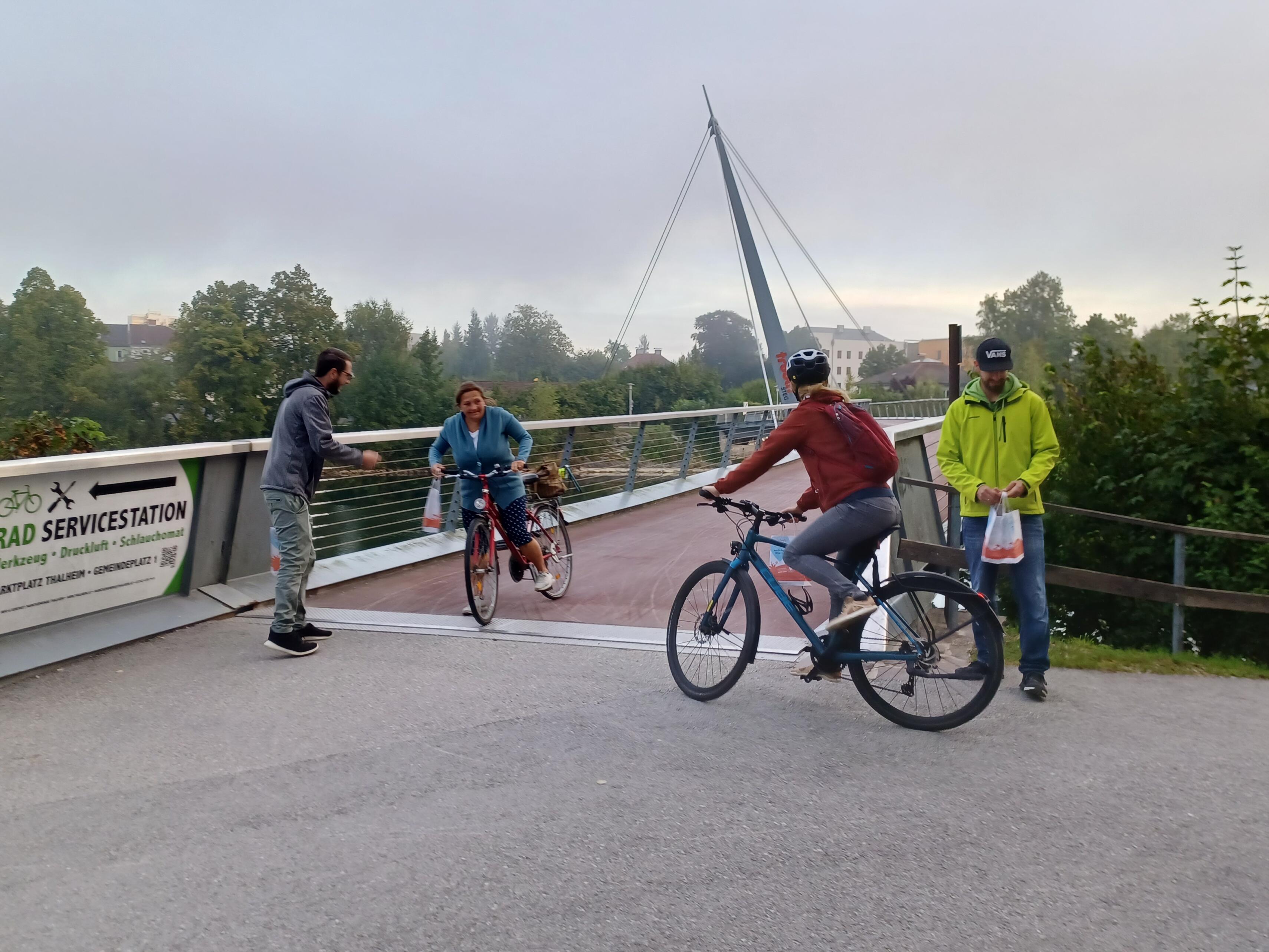 Fahrradfahrer mit Danke-Sackerl bei der Brücke