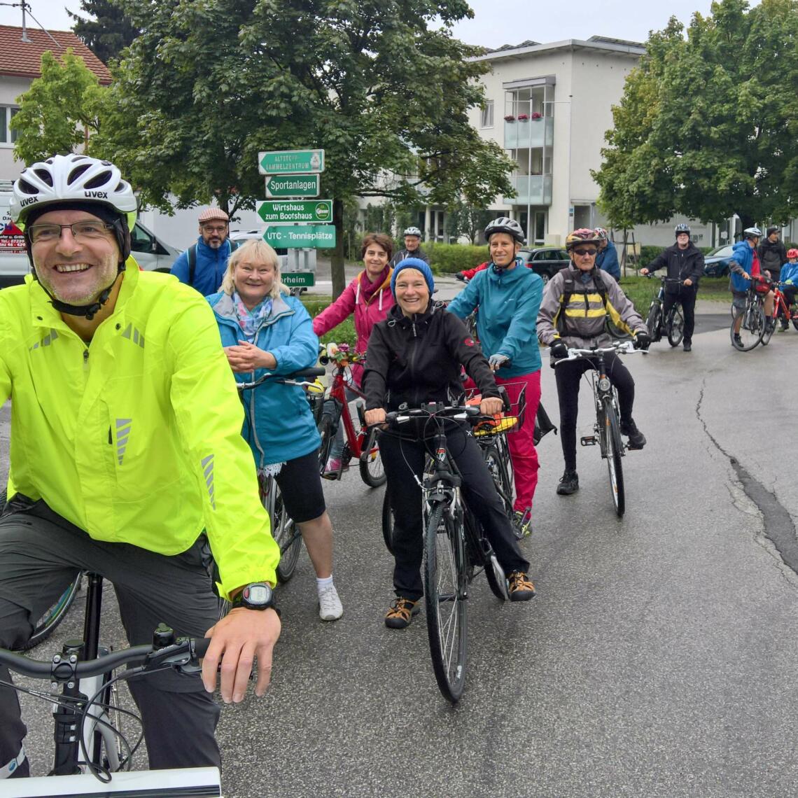 Foto von vielen Radfahrern die in einer mehrspurigen Linie fahren, vorderster Mann lächelt in die Kamera