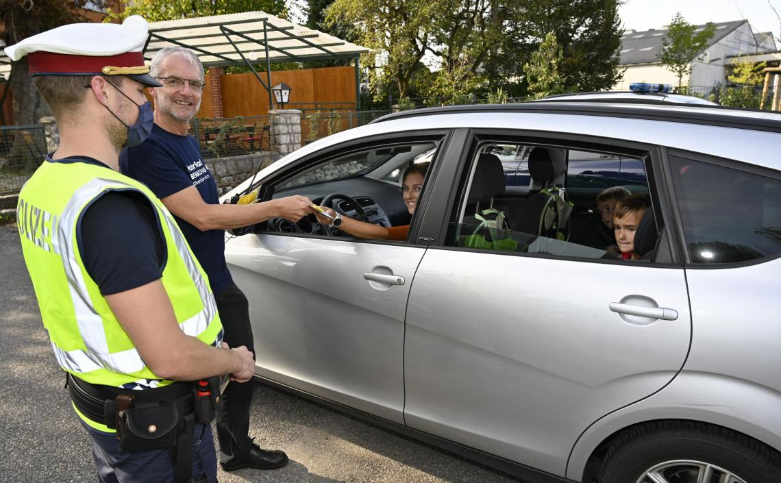 Personen mit PKW Herr und Polizist verteilen Flyer an Autofahrer