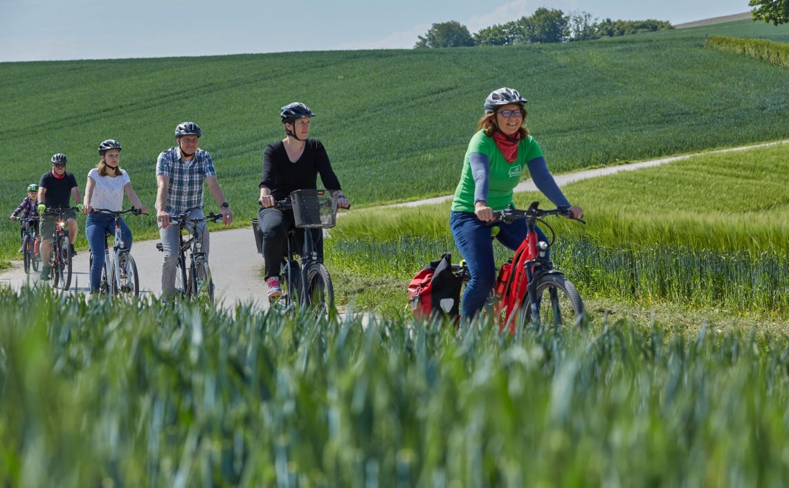 Familie auf Fahrrädern auf Straße neben Felder