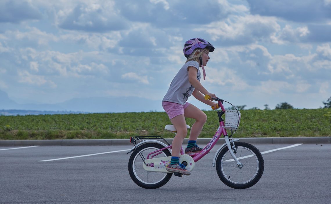 Mädchen auf Fahrrad auf Parkplatz