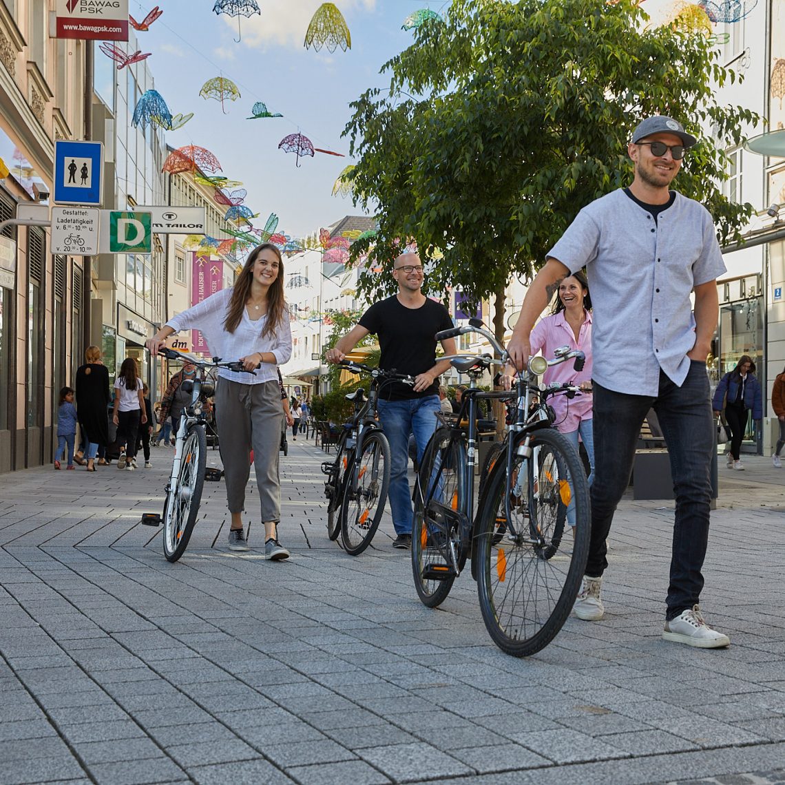 5 Personen schieben Fahrräder durch Altstadt