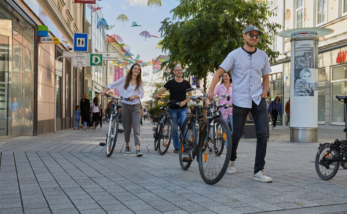 5 Personen schieben Fahrräder durch Altstadt