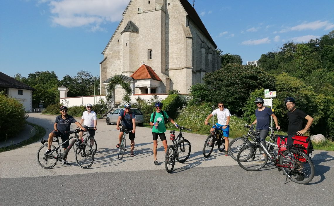 Personen mit Fahrrädern vor Kirche