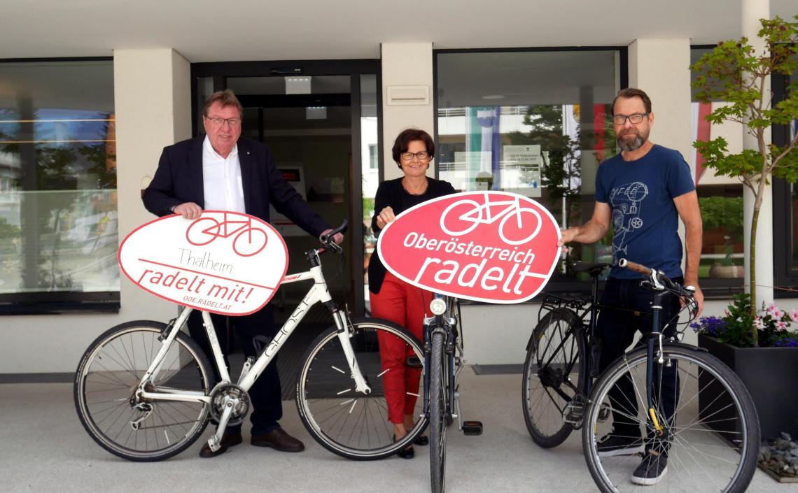 Personen mit Fahrrädern und Oberösterreich radelt Schildern