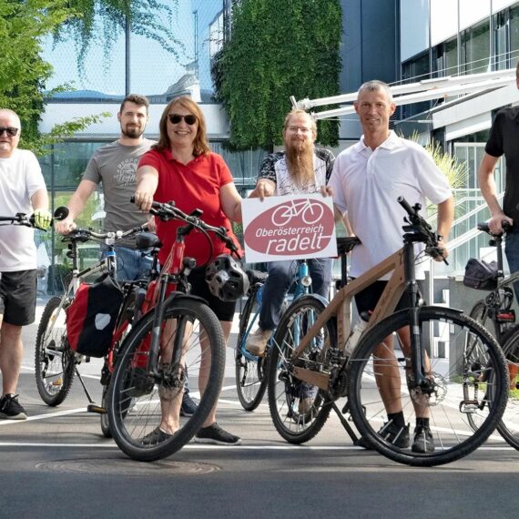 Personen mit Fahrrädern und Oberösterreich radelt Schildern